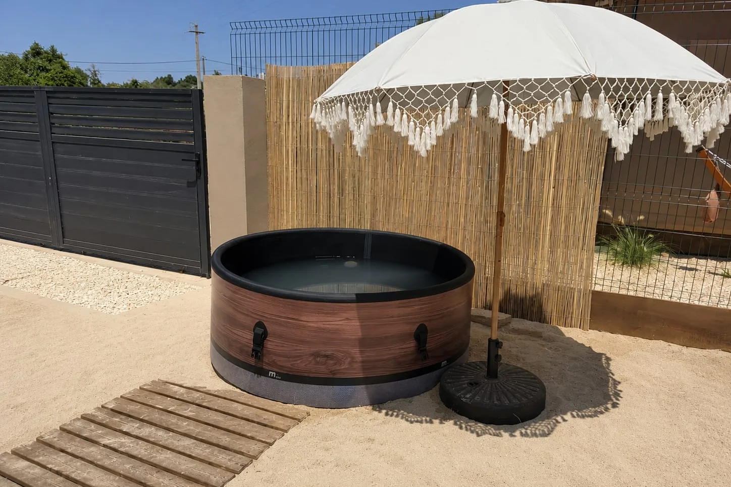 Eigen jacuzzi met parasol op het zandterras bij de Farm Lodge